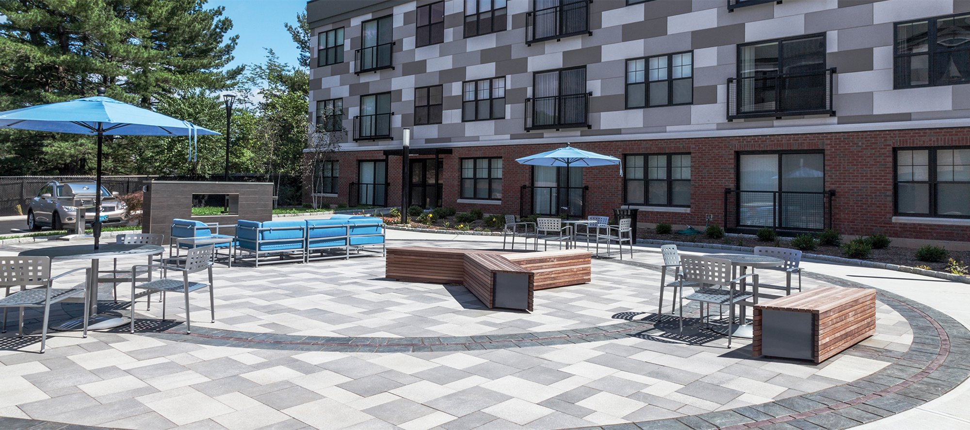 An apartment complex has an outdoor amenity space of Umbriano pavers with contrasting circular patterns of Copthorne and Richcliff.