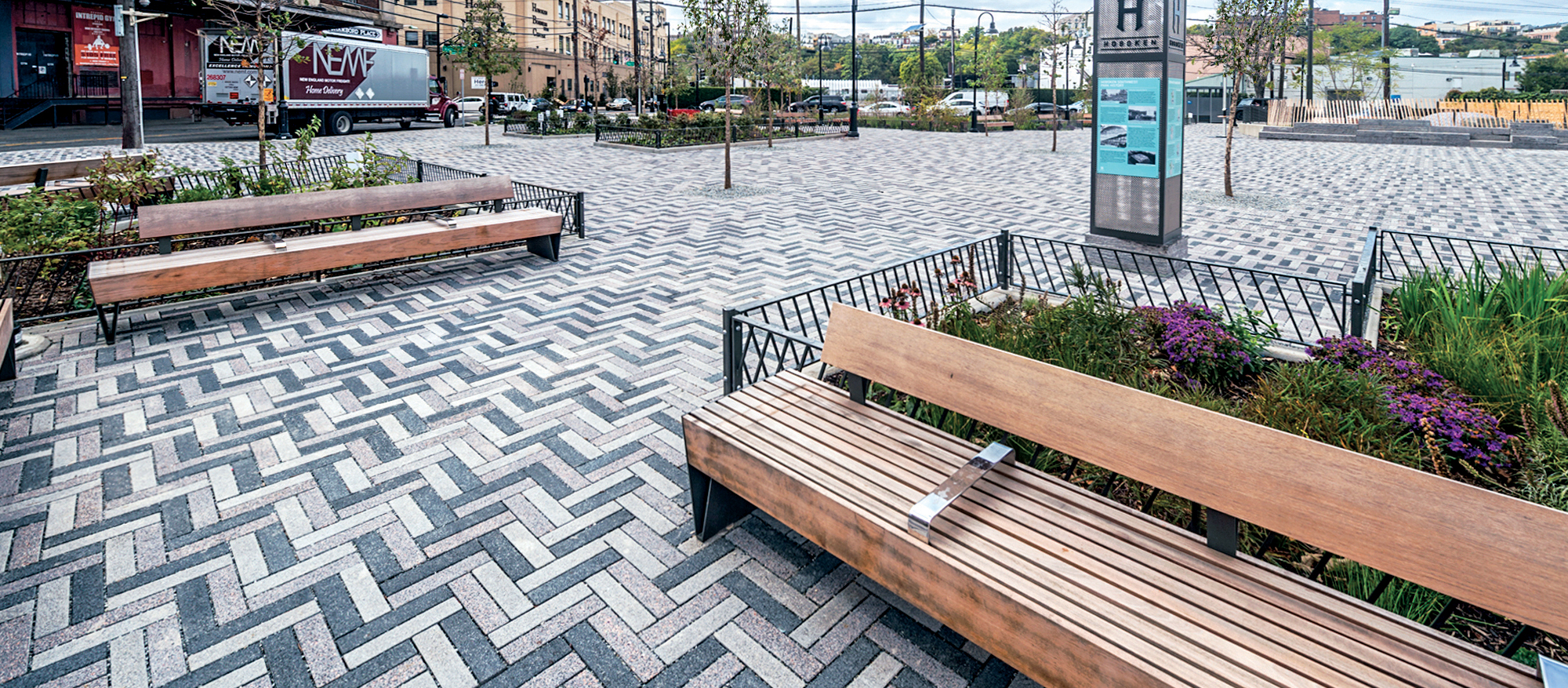 Tri-colored Eco-Promenade pavers provide visual flair when laid in a zigzag pattern, paired with surrounding garden beds and park benches.