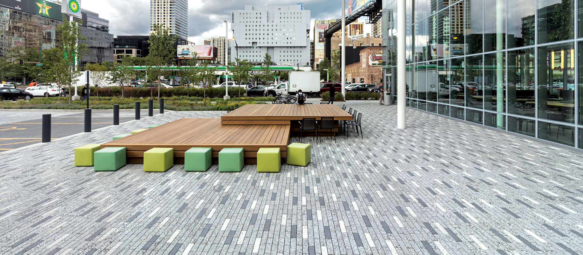 Eco-Promenade permeable pavers in different tones from white to dark grey with a speckled finish hold colorful seating blocks and tables.