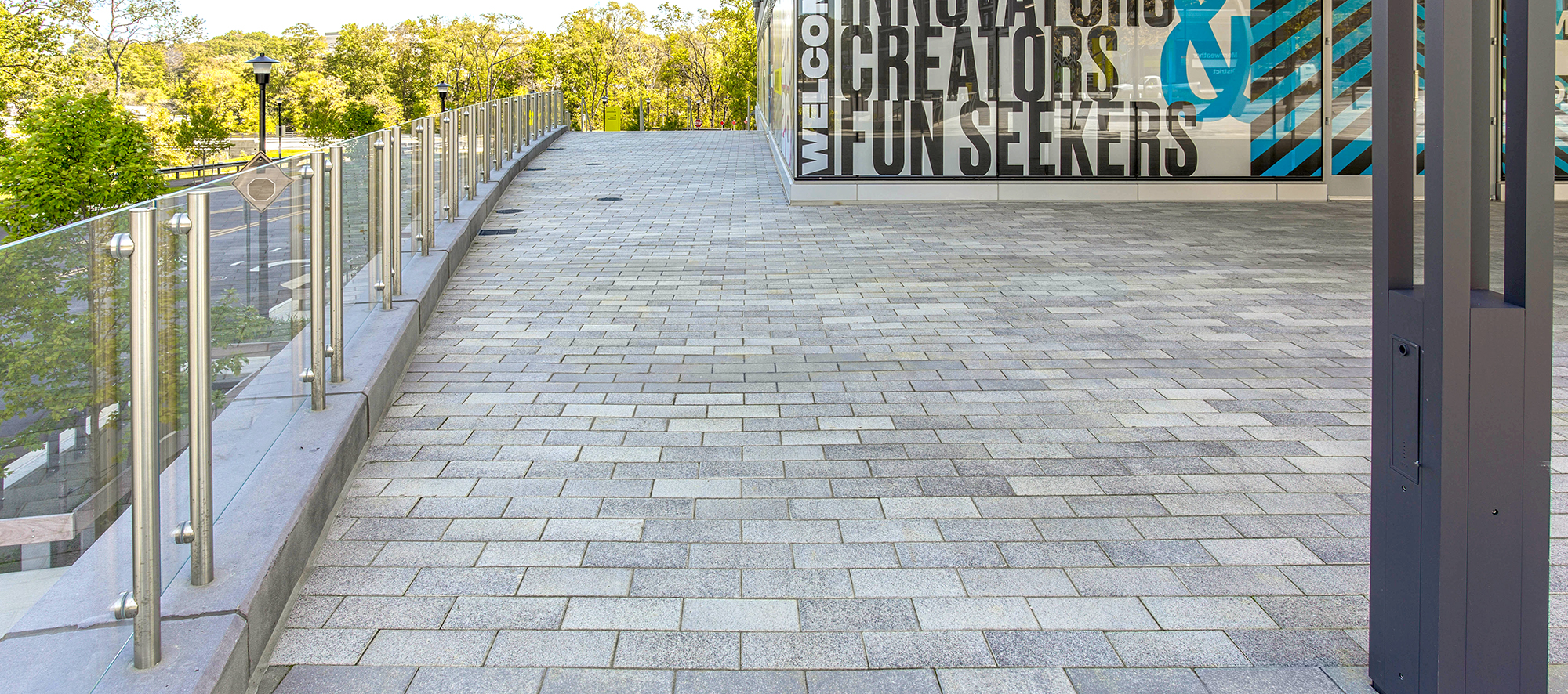 The blended tones of Promenade Plank Pavers allow for the deep colors of the building's inviting advertisement to stand out.